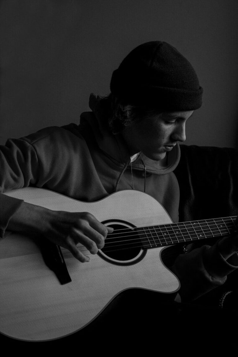 man in black knit cap playing acoustic guitar